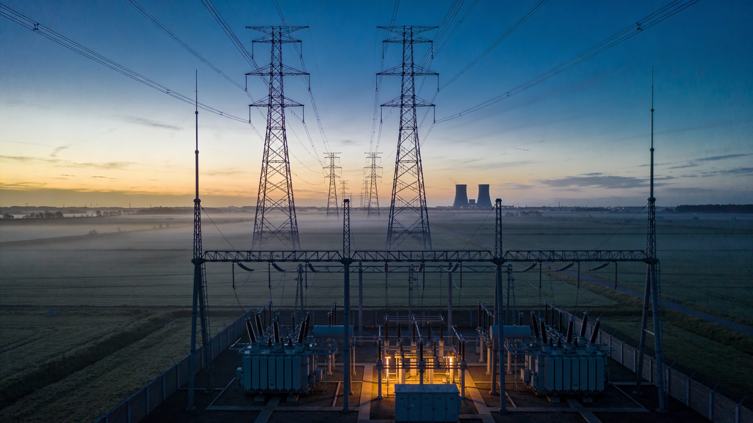 Hoogspanningsstation met masten in een Nederlands landschap bij schemering, symbool voor de groothandelsmarkt voor stroom